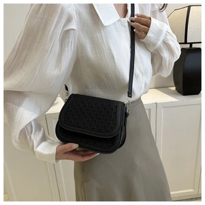 Detailed view of black woven texture leather crossbody saddle bag worn by a model