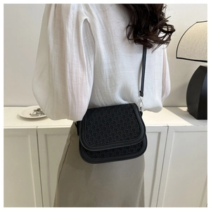 Detailed view of black woven texture saddle bag worn as a stylish crossbody on shoulder