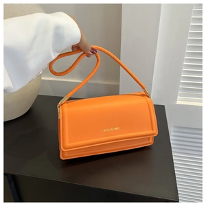 Detailweergave van de oranje lederen schoudertas met gouden logo en klepsluiting