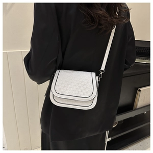 Detailed back view of white woven texture saddle bag with black trim and slim strap