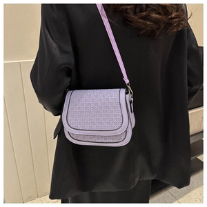 Detail of lavender woven saddle bag worn with a black blazer for a stylish look