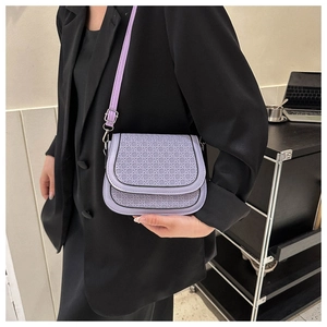Close-up of lavender woven saddle bag worn by a model in a black professional suit