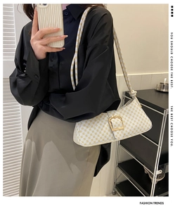 Modèle portant un sac baguette à monogramme blanc et jaune avec boucle dorée et cordon