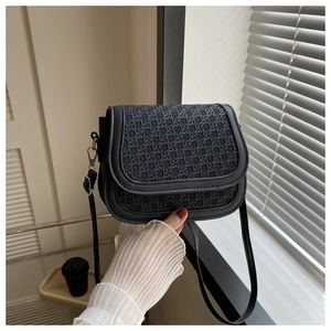 Close-up of black woven texture on saddle bag with silver buckles and a leather strap