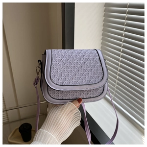 Detail of light purple saddle bag with woven texture flap and metallic clasp closure
