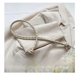 Détail de la grande boucle en U dorée et du motif rétro sur le sac à bandoulière crème