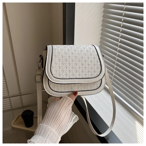 Close-up of woven texture white crossbody bag with black edges and gold metal buckle