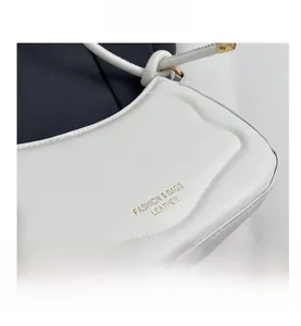 Detailansicht der weißen Satteltasche aus Leder mit goldener Logo-Prägung und Knotengurt