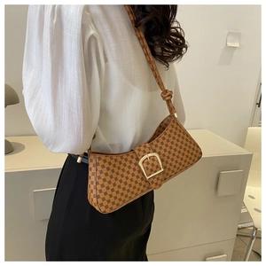 Détail d'un sac porté épaule vintage avec monogramme, boucle dorée et bandoulière nouée