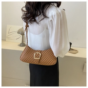 Détail du sac baguette vintage marron avec motifs géométriques et boucle dorée à l'épaule