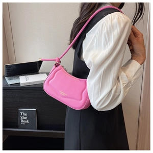 Detail der pinkfarbenen Schultertasche mit Wellentextur und goldener Beschriftung