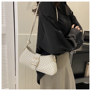 Détail du sac baguette à carreaux avec boucle dorée et bandoulière à nœud décoratif