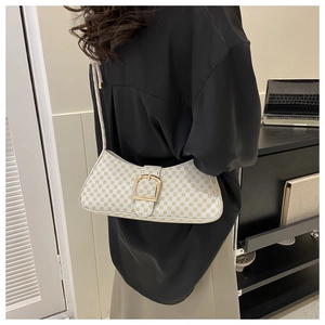 Sac baguette à carreaux porté à l'épaule sur un mannequin avec détails en cuir blanc élégant