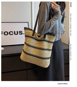 Detail of hand-woven straw tote with black stripes and slender leather shoulder strap