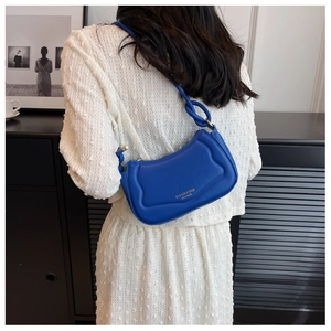 Detailansicht der blauen gesteppten Schultertasche aus Leder mit Knotengriff am Modell