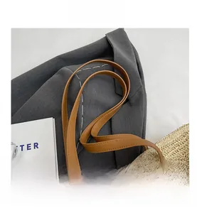 Detail of woven straw tote bag featuring brown leather straps and natural texture