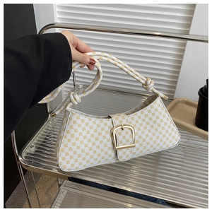 Détail du sac baguette vintage à motif géométrique avec grande boucle dorée et nœud