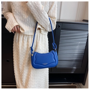 Details einer blauen gesteppten Schultertasche mit Knotengurt und Lederstruktur