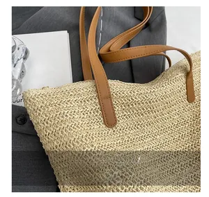 Detailed close-up of brown leather straps reinforced with stitching on a woven tote bag