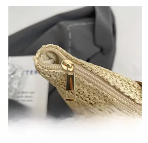 Detailed close-up of a smooth gold zipper and woven straw texture on a beige shoulder bag