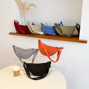 Minimalist nylon crescent crossbody bags in seven vibrant colors on a wooden shelf