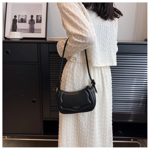 Detail einer Vintage-Schultertasche aus schwarzem Leder mit Ziernähten und Goldbeschlägen