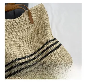 Close-up of beige straw tote bag showing black stripes and detailed woven fabric texture