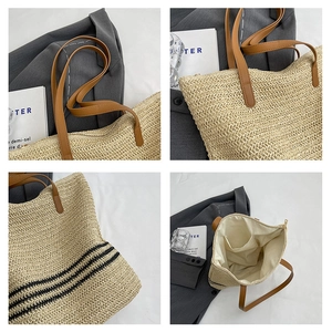 Detail view of woven straw tote bag featuring striped base, leather straps, and inner lining