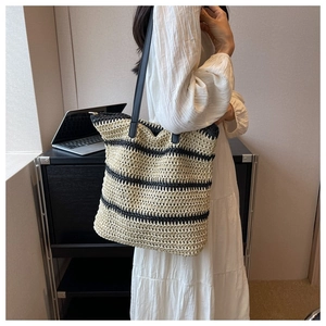 Detailed shot of striped woven straw tote bag with slim black leather shoulder straps