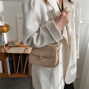 Minimalist beige half-moon leather crossbody bag with a gold oval metal lock and strap
