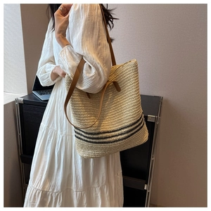 Detail of hand-woven straw tote with black stripes and brown leather double straps