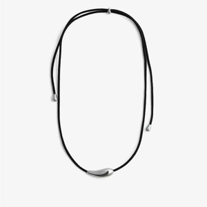 Detail shot of a polished silver teardrop pendant with a minimalist black woven cord