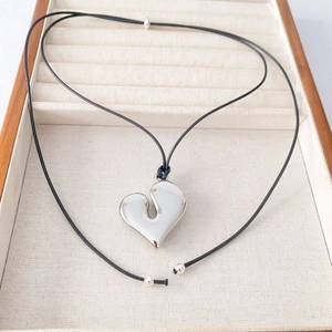 Artistic silver heart pendant necklace on black cord displayed in a wooden jewelry box