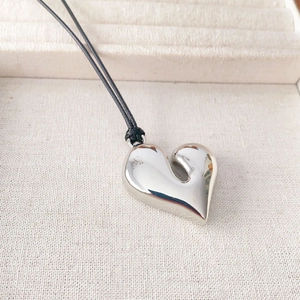 Minimalist silver heart pendant necklace with polished asymmetric design on black cord