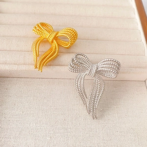 Broche nœud élégante avec texture perlée or et argent et détails de glands