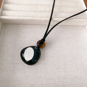 Modern black pebble pendant necklace with tiger eye bead on minimalist black cord