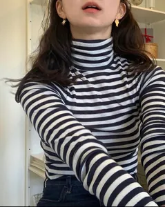 Gros plan d'un pull à col roulé rayé noir et blanc avec une coupe ajustée slim