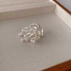 Minimalist silver-tone tassel fireworks ring with pearls on a wooden jewelry tray