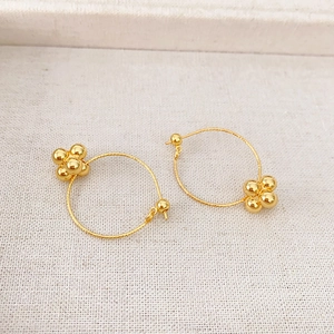 Minimalist gold-plated hoop earrings featuring a cluster of four delicate golden beads