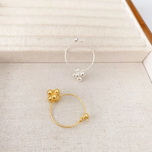 Fashionable gold and silver plated hoop earrings with dangling cluster beads on beige display