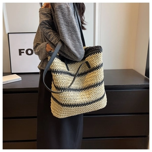 Close-up of black and white striped woven tote bag with leather straps on a model