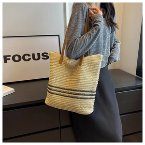Detail of hand-woven straw tote bag with contrasting stripes and brown leather straps