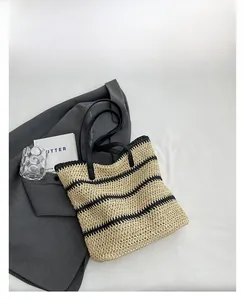 Top view of woven straw tote bag with black horizontal stripes and faux leather handles