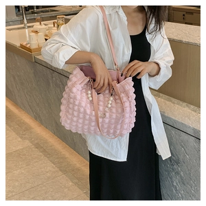 Detail of pink ruched plissé tote bag showing bubble texture and pearl strap detail