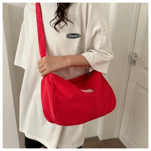 Dettaglio della borsa a tracolla rossa in nylon con etichetta moda su modella donna