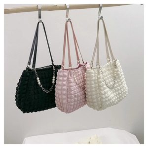 Three pleated bubble tote bags with pearl flower chains hanging on a wooden rack