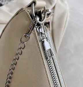 Close-up of smooth silver zipper and durable metal hardware on beige saddle bag
