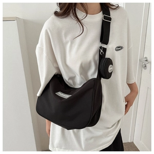 Dettaglio borsa a tracolla in nylon nero con pochette rotonda ed etichetta moda