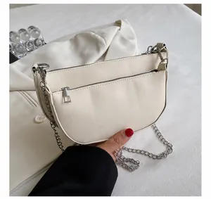 Close-up of white leather saddle bag with silver chain strap and front zipper pocket