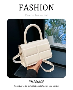 Close-up of cream quilted crossbody bag with top handle and textured faux leather detail